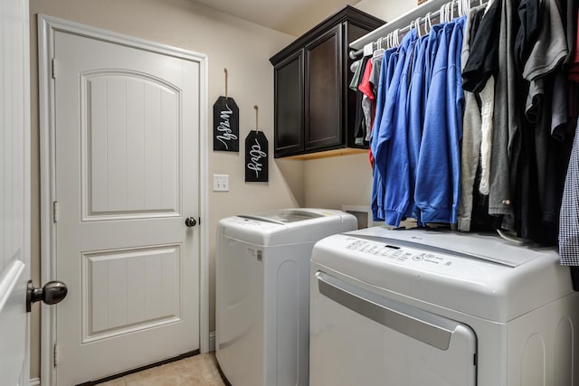 clothes washing area with light tile patterned floors, washer and clothes dryer, and cabinet space