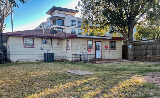 back of house with cooling unit and a lawn