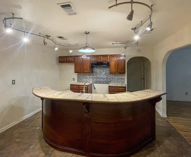 kitchen featuring tile counters, backsplash, and decorative light fixtures