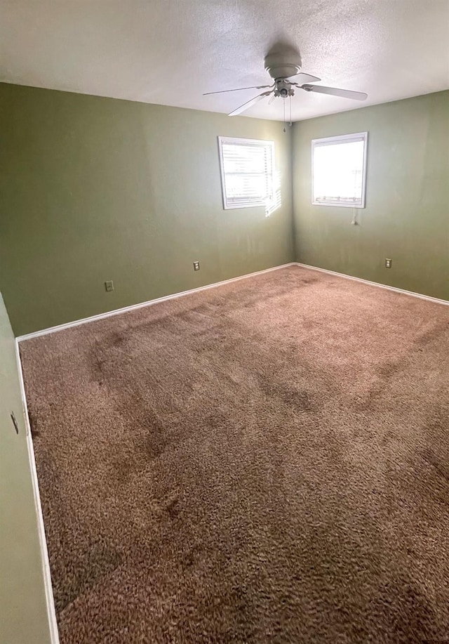 carpeted spare room with a textured ceiling and ceiling fan