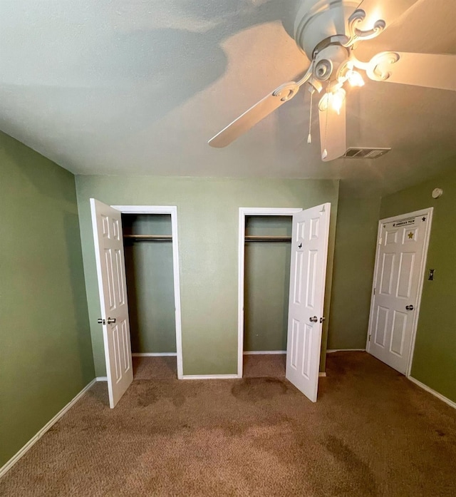 unfurnished bedroom featuring two closets, ceiling fan, and carpet