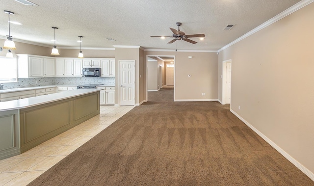 kitchen with hanging light fixtures, ornamental molding, white cabinets, decorative backsplash, and light colored carpet