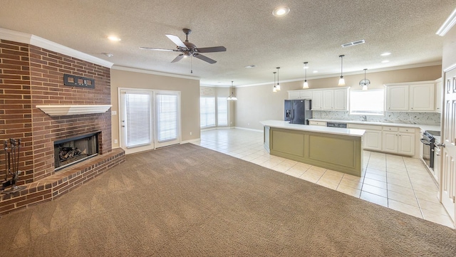 kitchen featuring pendant lighting, light tile patterned floors, white cabinetry, a center island, and black appliances