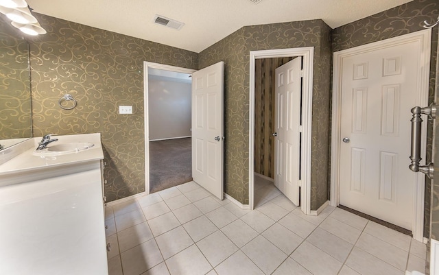 bathroom featuring tile patterned flooring, vanity, and a textured ceiling