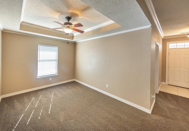 carpeted spare room with a raised ceiling, ornamental molding, and ceiling fan