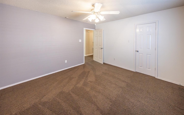 empty room featuring ceiling fan, a textured ceiling, and dark carpet