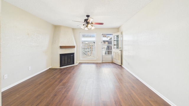 5768 38th St, Lubbock, TX 79407 - unfurnished living room featuring ceiling fan, a textured ceiling, a large fireplace, baseboards, and dark wood finished floors