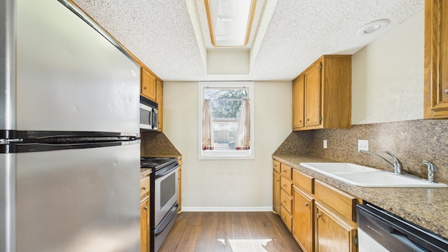 5768 38th St, Lubbock, TX 79407 - kitchen with decorative backsplash, appliances with stainless steel finishes, dark wood-type flooring, a sink, and a textured ceiling