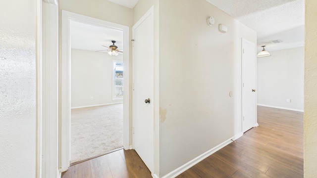 5768 38th St, Lubbock, TX 79407 - corridor featuring a textured ceiling, baseboards, and wood finished floors