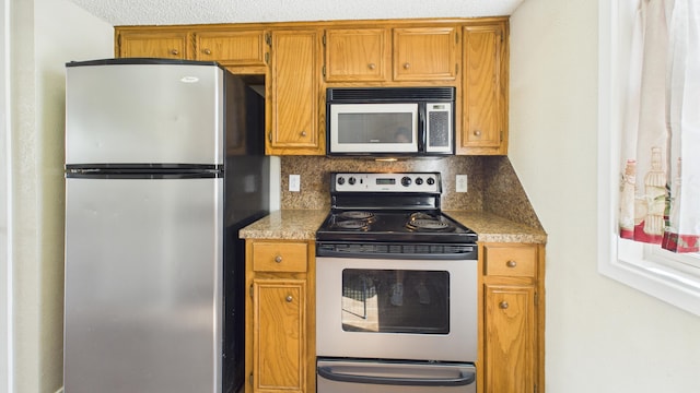 5768 38th St, Lubbock, TX 79407 - kitchen with appliances with stainless steel finishes, brown cabinetry, and backsplash