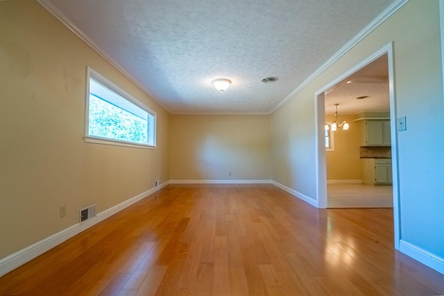 unfurnished room featuring crown molding, a notable chandelier, light hardwood / wood-style flooring, and a textured ceiling