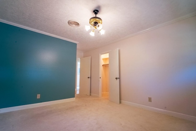 empty room with ceiling fan, light colored carpet, ornamental molding, and a textured ceiling