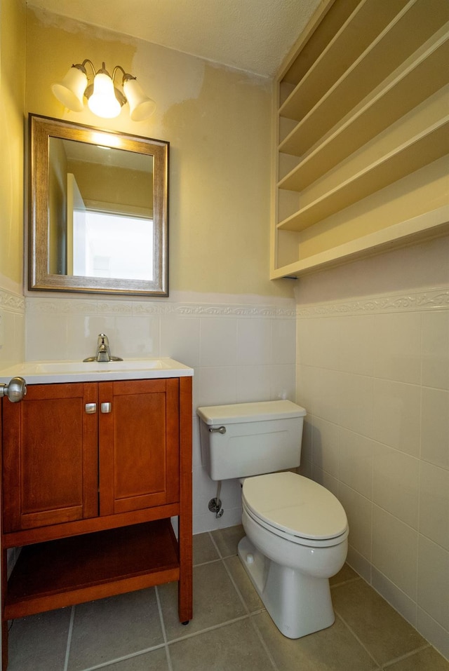 bathroom with tile patterned flooring, vanity, tile walls, and toilet