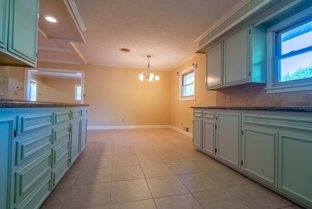 kitchen featuring an inviting chandelier, light tile patterned floors, ornamental molding, pendant lighting, and decorative backsplash