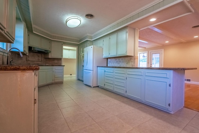 kitchen with light tile patterned floors, backsplash, ornamental molding, kitchen peninsula, and white fridge