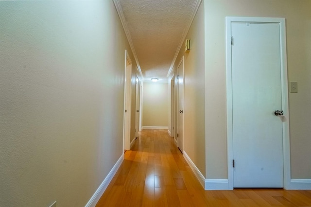 hall with ornamental molding, a textured ceiling, and light wood-type flooring