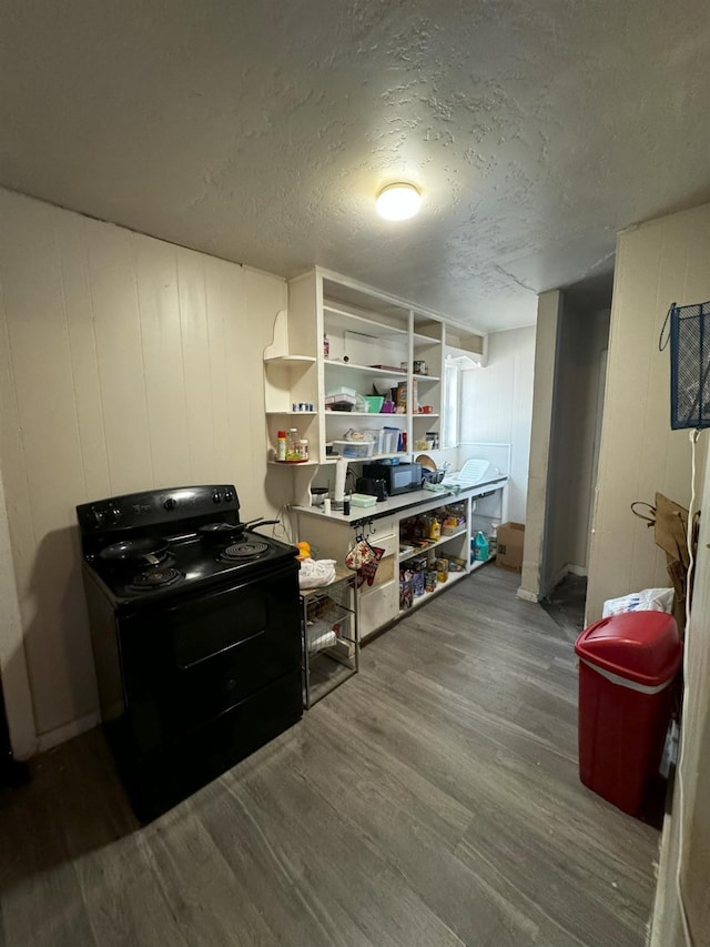 interior space with wood walls, white cabinetry, a textured ceiling, electric range, and hardwood / wood-style flooring