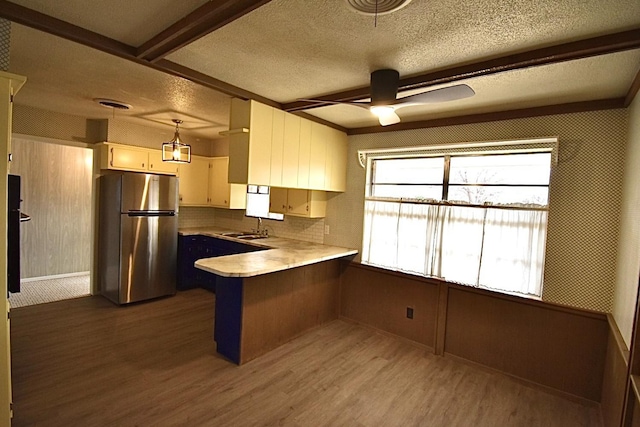 kitchen featuring sink, decorative light fixtures, stainless steel refrigerator, kitchen peninsula, and light hardwood / wood-style floors