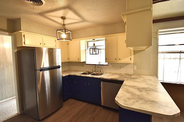 kitchen featuring appliances with stainless steel finishes, pendant lighting, white cabinetry, sink, and kitchen peninsula