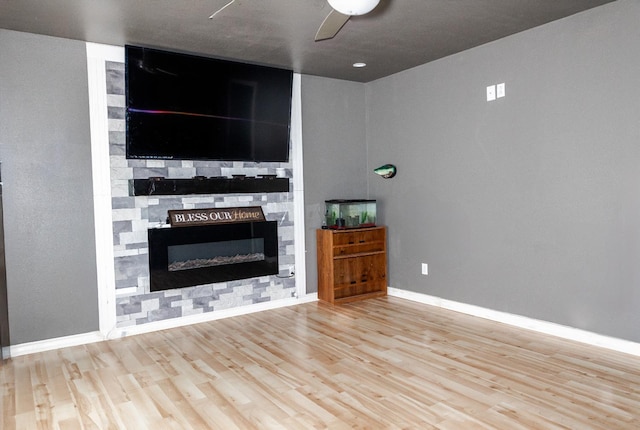 unfurnished living room with ceiling fan, a fireplace, and light hardwood / wood-style flooring