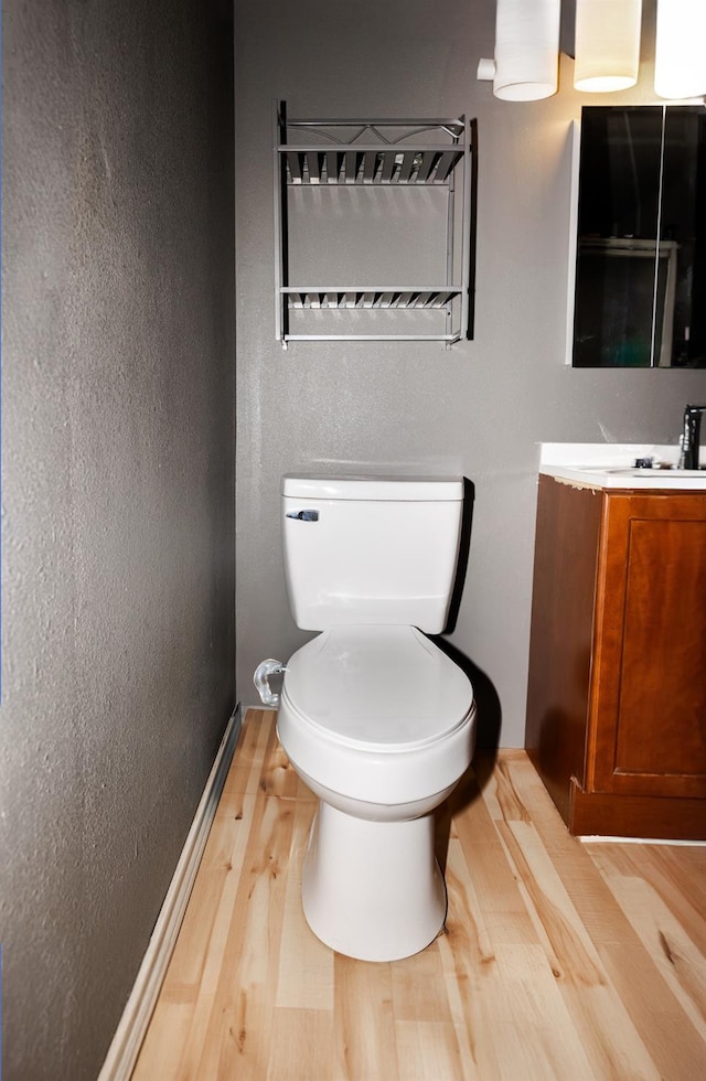 bathroom with hardwood / wood-style flooring, vanity, and toilet