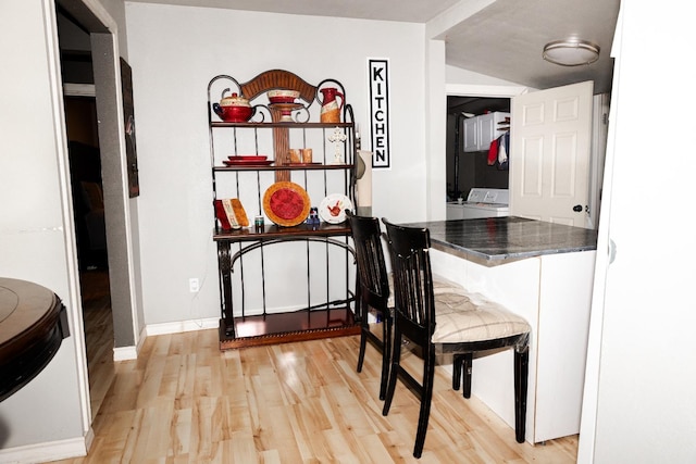 bar featuring white cabinetry, washer / dryer, and light hardwood / wood-style floors