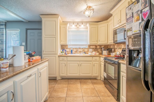 kitchen with sink, black appliances, a textured ceiling, light tile patterned floors, and backsplash