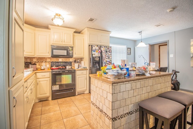 kitchen featuring a center island, hanging light fixtures, light tile patterned floors, decorative backsplash, and black appliances