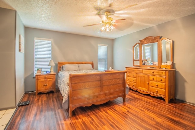 bedroom featuring ceiling fan, wood-type flooring, and a textured ceiling