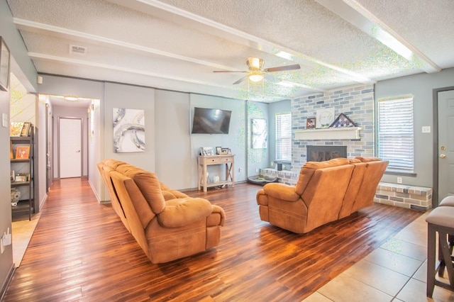 living room with beamed ceiling, plenty of natural light, a fireplace, and a textured ceiling