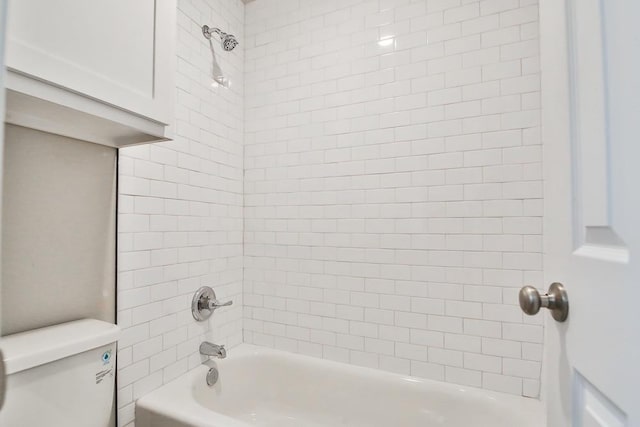 bathroom featuring tiled shower / bath and toilet