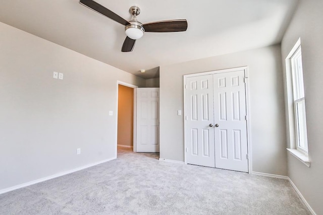 unfurnished bedroom featuring multiple windows, light colored carpet, ceiling fan, and a closet