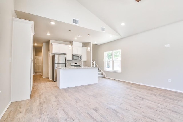 kitchen with pendant lighting, stainless steel appliances, a center island with sink, and white cabinets