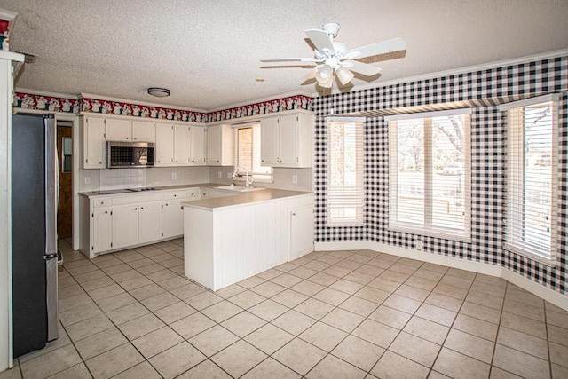 kitchen featuring stainless steel appliances, white cabinetry, a textured ceiling, and kitchen peninsula