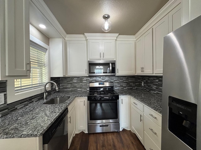 kitchen featuring sink, dark wood-type flooring, appliances with stainless steel finishes, white cabinets, and dark stone counters