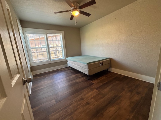 unfurnished bedroom with a textured ceiling, dark wood-type flooring, and ceiling fan