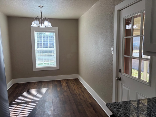 unfurnished dining area with a wealth of natural light, dark wood-type flooring, and a chandelier