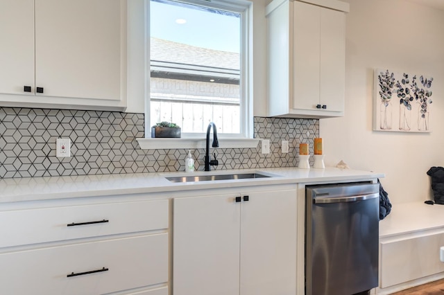 kitchen featuring a sink, tasteful backsplash, white cabinetry, light countertops, and stainless steel dishwasher