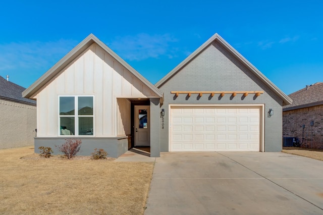 view of front facade with board and batten siding, brick siding, a garage, driveway, and cooling unit