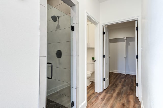 full bathroom with toilet, a shower stall, wood finished floors, and baseboards