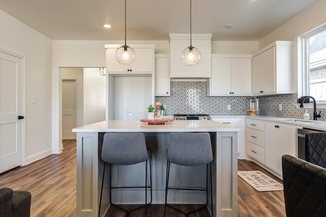 kitchen featuring a breakfast bar area, white cabinetry, decorative backsplash, and a sink