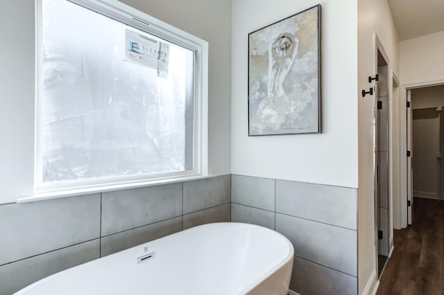 bathroom with wood finished floors and a soaking tub