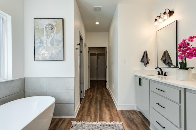 bathroom with visible vents, recessed lighting, a freestanding tub, wood finished floors, and vanity