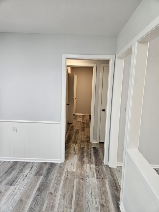 corridor with wood finished floors and a wainscoted wall