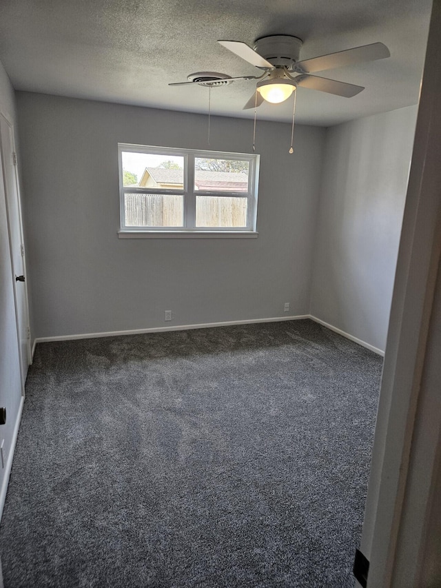 spare room with dark colored carpet, ceiling fan, and baseboards