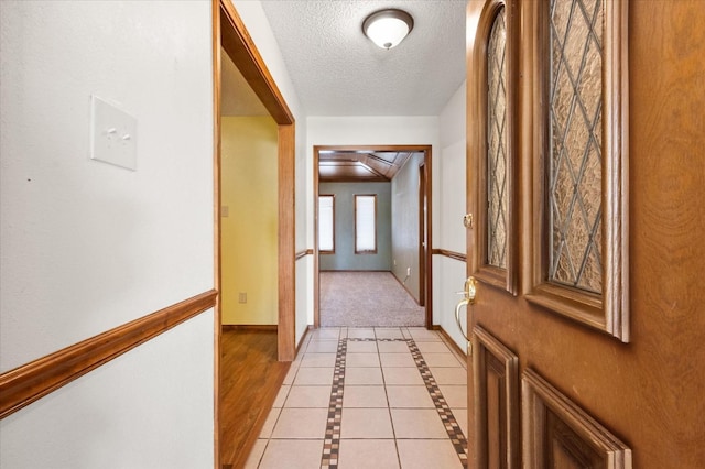 corridor featuring a textured ceiling and light tile patterned floors