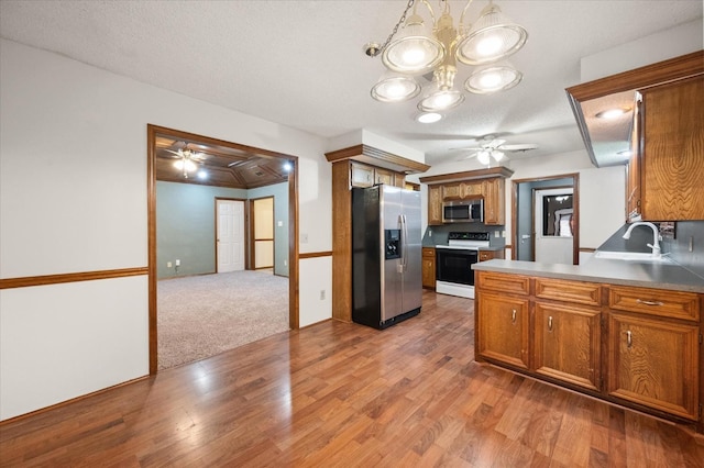 kitchen featuring sink, ceiling fan with notable chandelier, light hardwood / wood-style floors, and appliances with stainless steel finishes