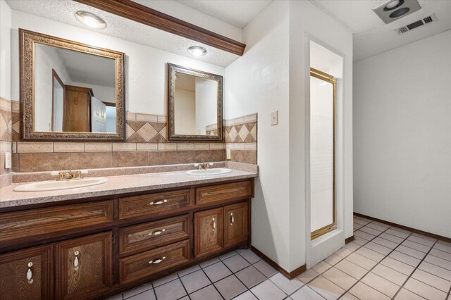 bathroom with vanity, tile patterned flooring, a shower with shower door, and a textured ceiling