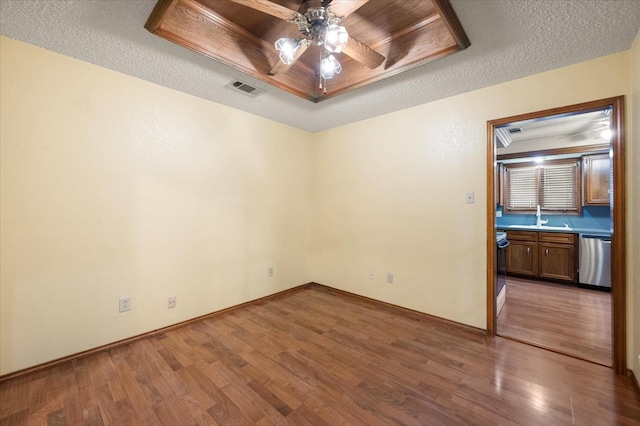 empty room featuring a raised ceiling, hardwood / wood-style floors, and a textured ceiling