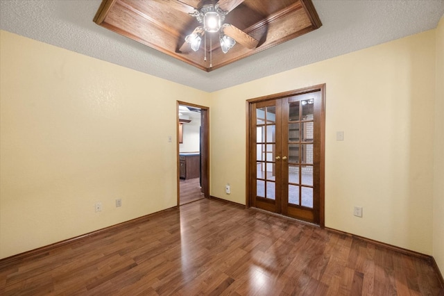 spare room with hardwood / wood-style floors, ceiling fan, a raised ceiling, a textured ceiling, and french doors